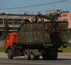 Full garbage truck driving down a road.