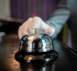 Bellhop hand about to ring front desk bell.